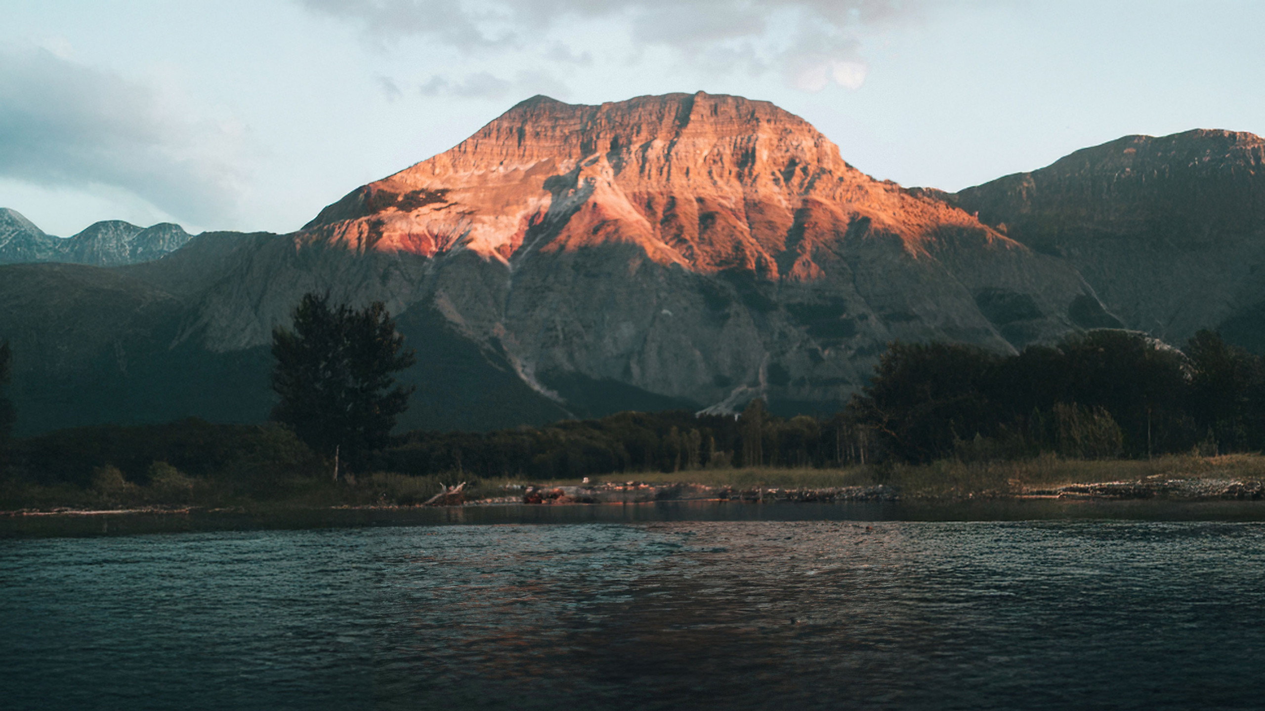 Sunlit mountain rising above a lake at dusk